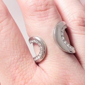 Bague ouverte argentée portée au doigt avec strass brillants