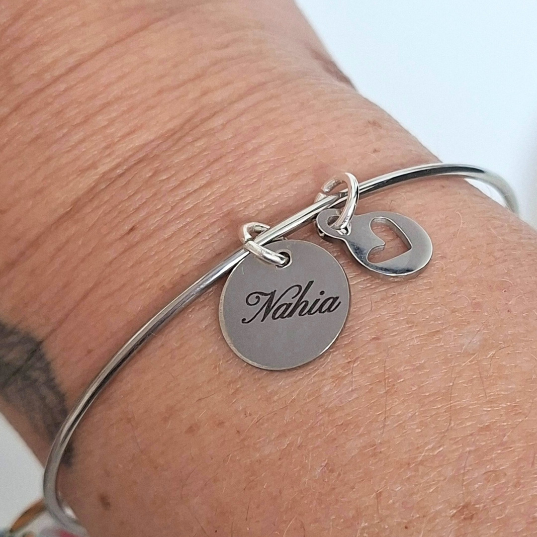 Bracelet jonc gravé porté au poignet avec médailles prénom et cœur – acier inoxydable argenté