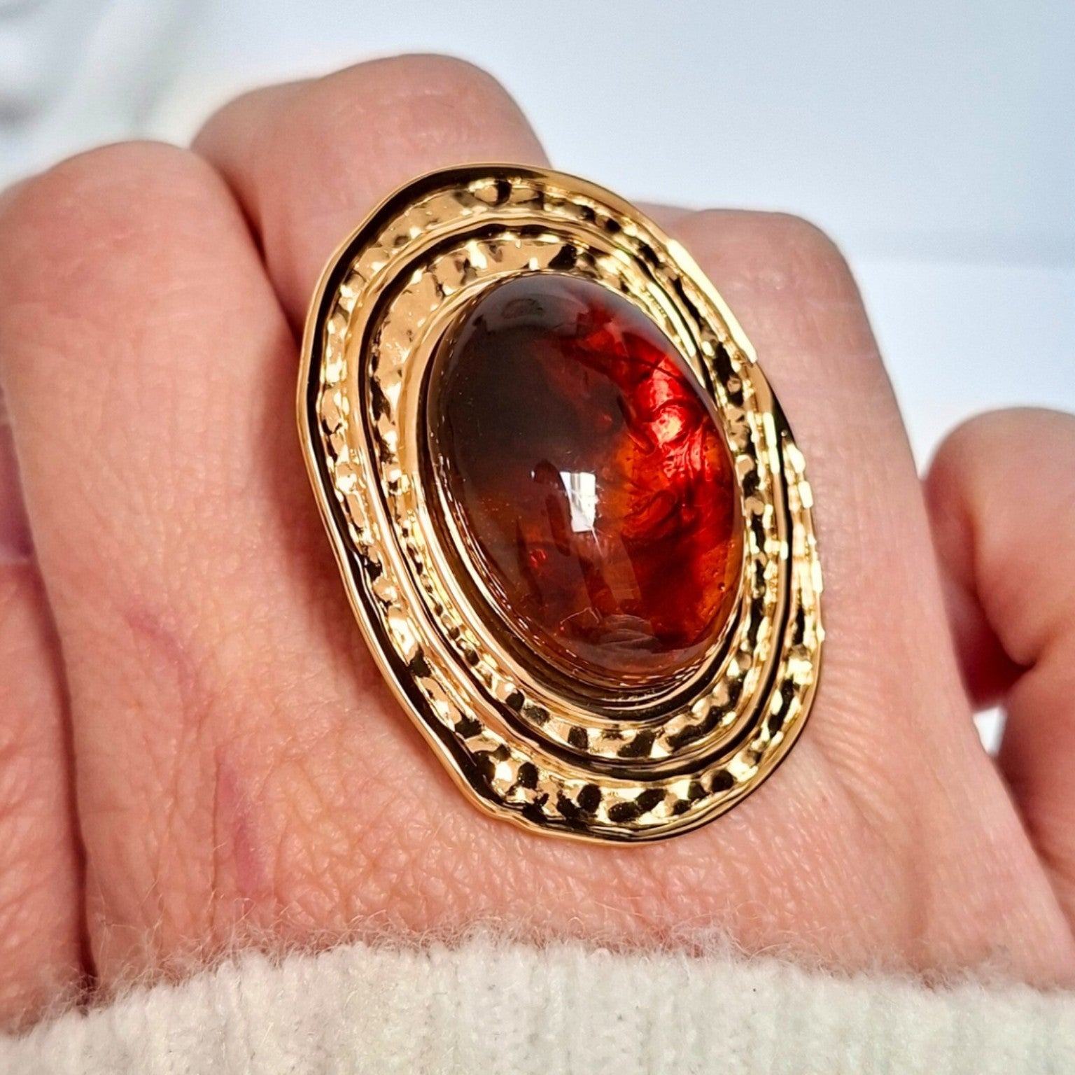 Bague dorée ovale effet ambre portée sur la main