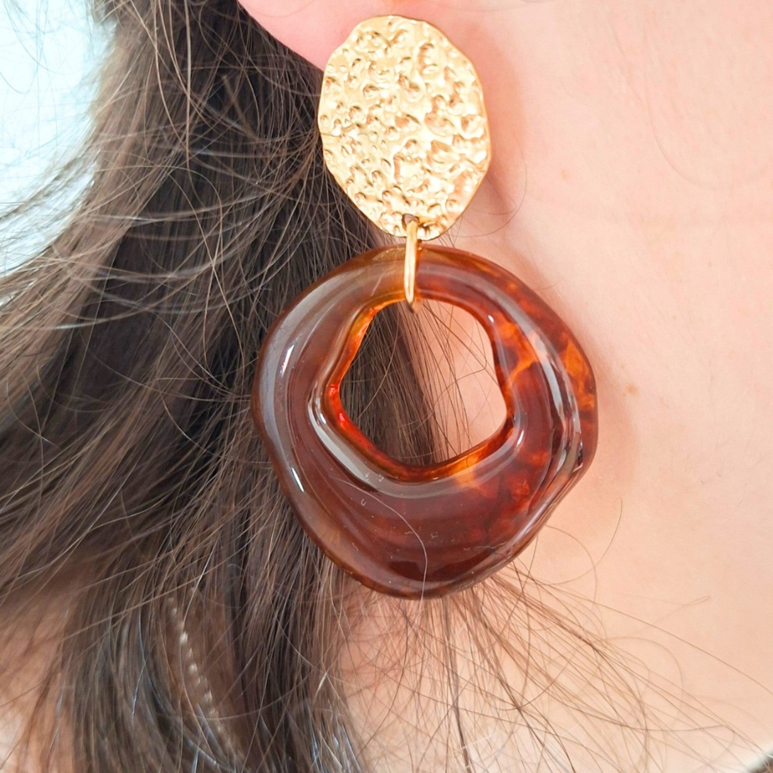 Boucle d’oreille dorée et résine ambrée portée sur oreille femme