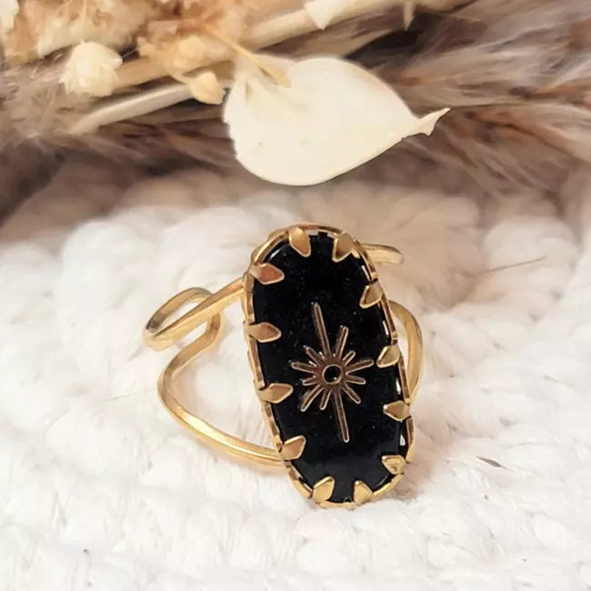 Bague dorée avec pierre noire portée au doigt femme