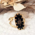 Bague ajustable dorée avec pierre noire et motif étoile sur fond clair