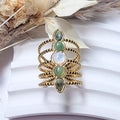 Bague dorée femme multi-rangs en acier inoxydable ajustable, décorée de cabochons verts et blanc nacré — vue portée au doigt.