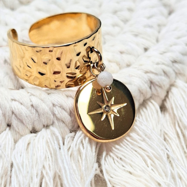 Bague en acier doré martelé avec pendentif étoile et perle blanche portée au doigt
