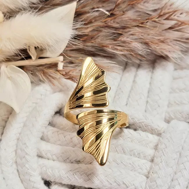 Bague ajustable dorée en acier inoxydable, design feuille de ginkgo biloba, portée au doigt d’une femme