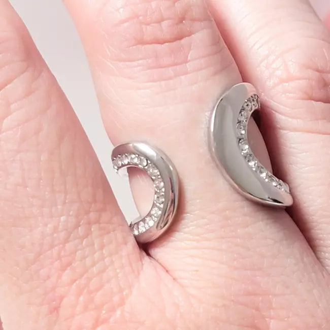 Bague ouverte argentée portée au doigt avec strass brillants