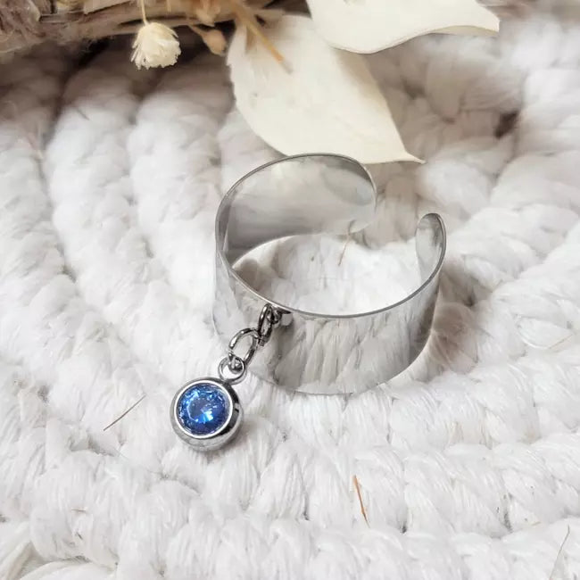 Bague personnalisée en acier inoxydable argenté avec pierre de naissance bleue, portée au doigt