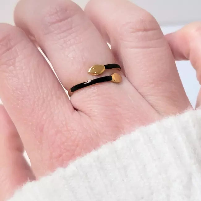 Bague serpent noire et dorée en acier inoxydable ajustable, portée au doigt d’une femme