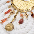 Détail des pampilles dorées et perles orangées sur boucles d’oreilles bohème chic femme