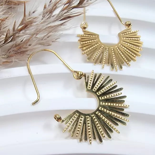 Gros plan boucle d’oreille soleil dorée en acier inoxydable pour femme
