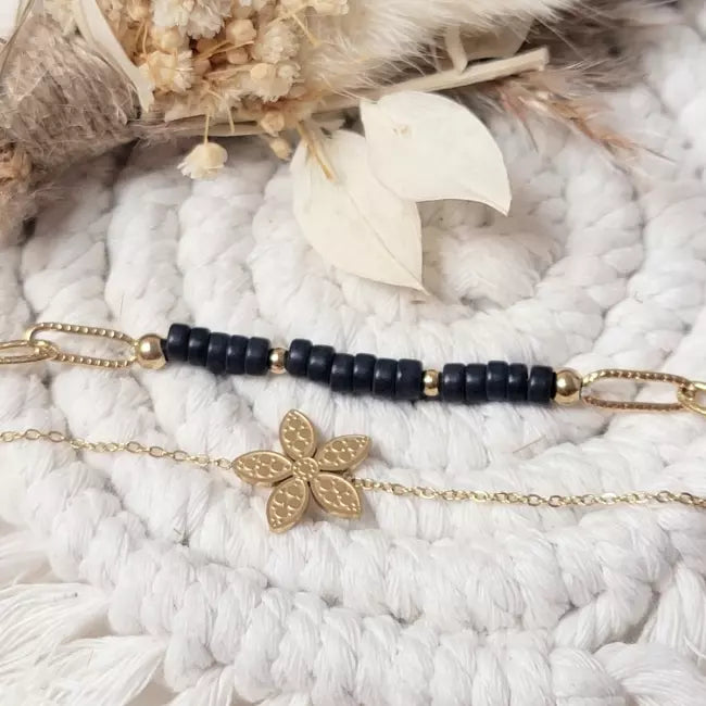 Bracelet femme doré et noir en acier inoxydable avec fleur élégante porté au poignet