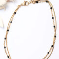 Chaîne de cheville femme dorée en acier inoxydable avec perles noires