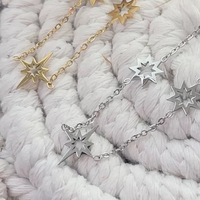 Collier doré en acier inoxydable porté, pendentifs étoiles du nord ajourées réparties sur une fine chaîne.