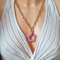 Collier fleur rose en acrylique porté, pendentif en forme de fleur sur chaîne dorée à gros maillons.