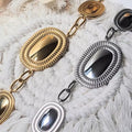 Colliers larges en acier inoxydable doré et argenté, pendentifs ovales texturés alignés, présentation à plat.