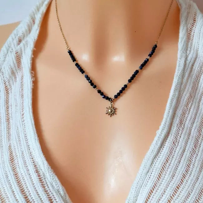 Collier soleil doré avec perles facettées bleu marine, pendentif doré en forme de soleil.