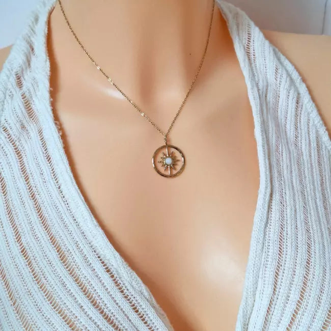 Collier soleil doré porté, pendentif rond avec pierre verte centrale, chaîne fine en acier inoxydable.