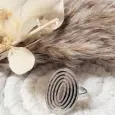 Bague ovale argentée en acier inoxydable sur fond naturel avec fleurs séchées et macramé blanc