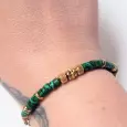 Bracelet vert porté – perles striées et détails dorés sur fond neutre