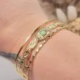 Bracelet jonc doré en acier inoxydable porté au poignet, cabochon vert, manchette ajustable style boheme.