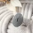 Bague spirale argentée à motif ovale posée sur un support en corde torsadée blanche