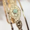 Gros plan sur le cabochon vert et la texture perlée du bracelet jonc manchette doré en acier inoxydable