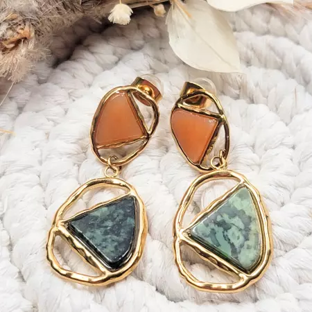 Boucles d’oreilles pendantes dorées avec pierres vertes et oranges posées sur une corde tressée