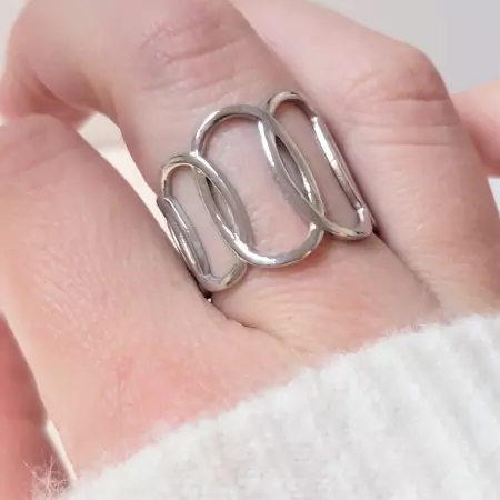 Bague ajourée en acier inoxydable argenté portée sur la main, design graphique moderne