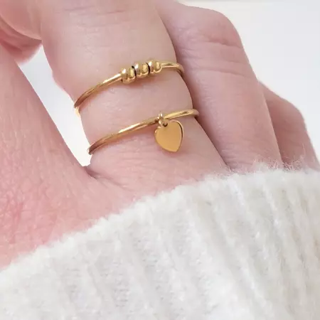 Bague dorée double avec perles et cœur portée sur doigt – acier inoxydable