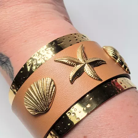 Bracelet manchette camel porté au poignet, vue rapprochée des reliefs dorés marins.
