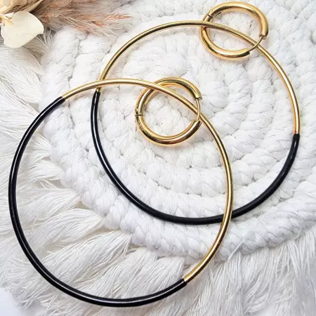 Gros plan sur boucles d'oreilles créoles en acier inoxydable doré et noir, petites créoles de 2 cm et grandes créoles de 6 cm, avec anneaux entrelacés sur fond blanc.