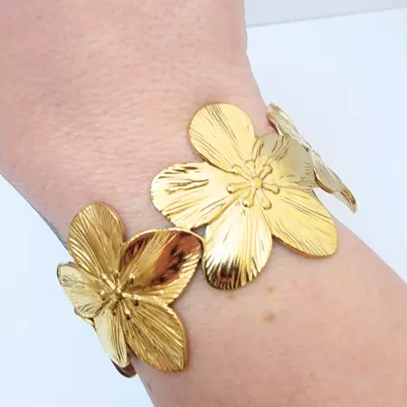 Bracelet manchette en acier inoxydable avec motif floral gravé, disponible en doré et argenté. Bijou élégant et résistant, idéal pour femme, parfait comme cadeau ou accessoire de mode.