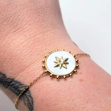 Bracelet solaire nacre porté au poignet avec tatouage visible