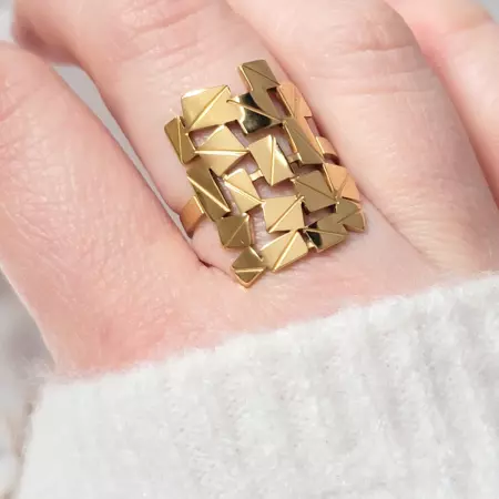 bague moderne dorée portée sur doigt femme pull blanc