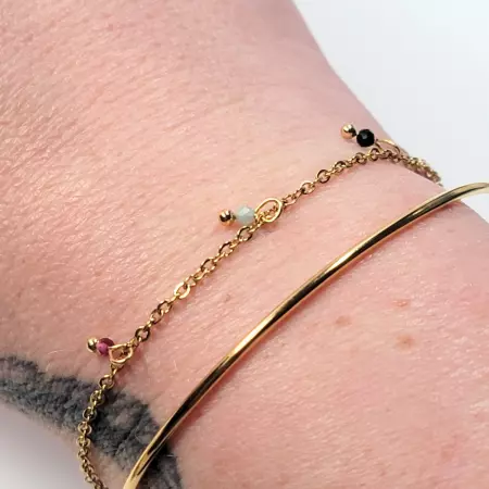 bracelet jonc doré et chaîne fine avec perles porté au poignet femme