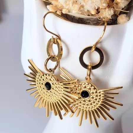 Boucles soleil doré portées sur support blanc avec fleurs séchées décoratives