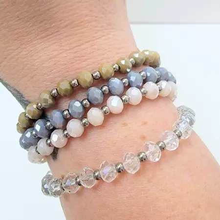 Bracelets empilés en perles facettées marron,bleu, rose et transparente portés ensemble.