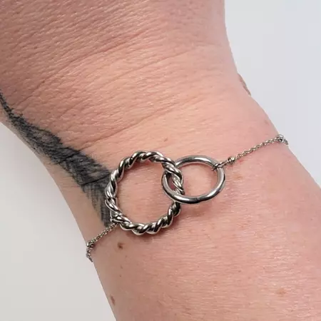Bracelet minimaliste en acier inoxydable porté au poignet, avec anneaux entrelacés