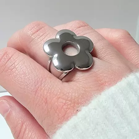 Bague fleur argentée portée sur la main, style moderne et lumineux