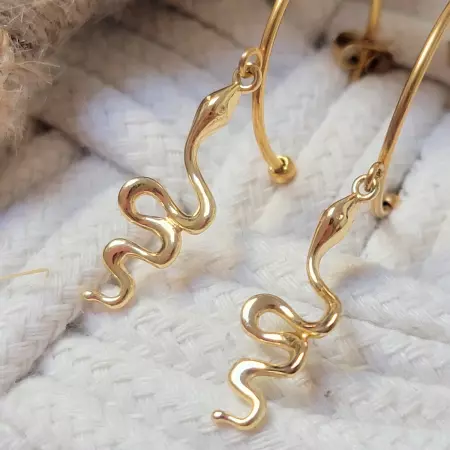 Gros plan sur les pendentifs serpent doré, détail du mouvement ondulé et du poli miroir