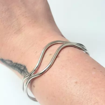 Bracelet jonc vague argenté porté au poignet