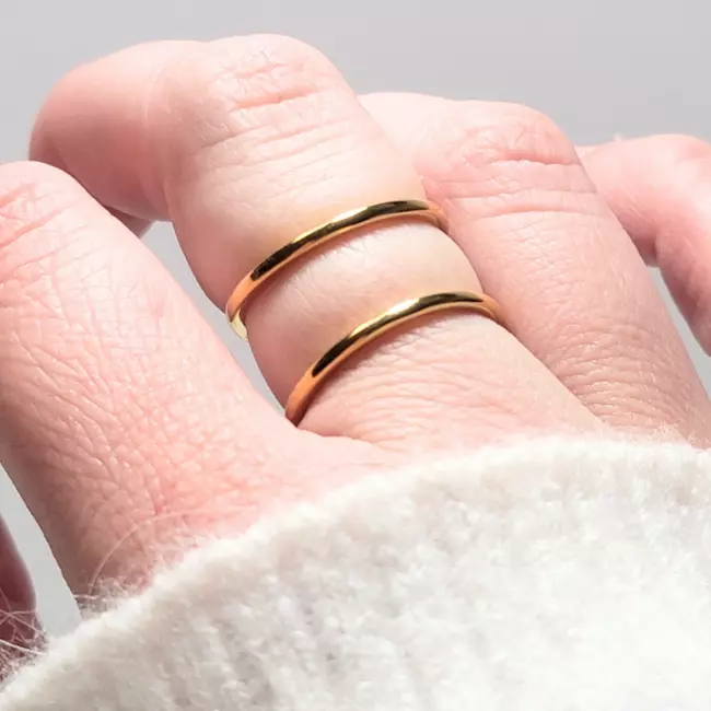 Main portant une bague double dorée en acier inoxydable à effet miroir