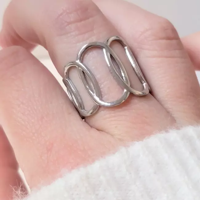 Bague ajourée en acier inoxydable argenté portée sur la main, design graphique moderne