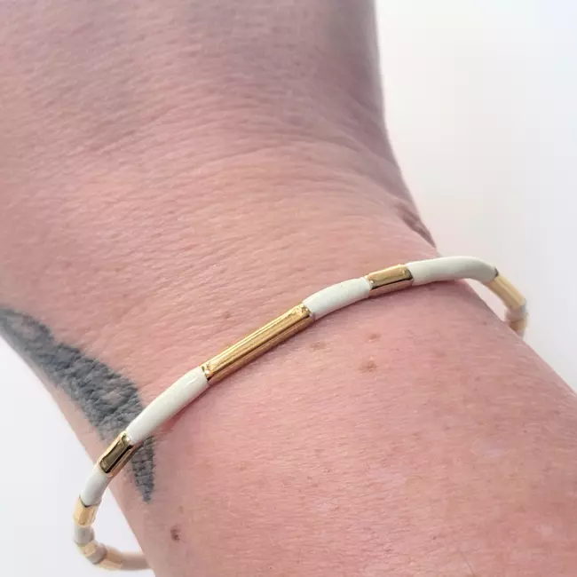 Jonc blanc et doré porté au poignet – bracelet rigide femme chic