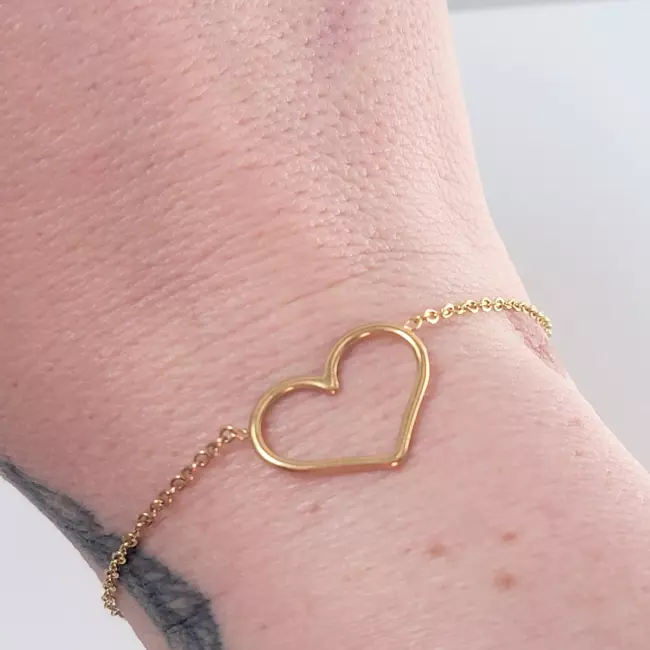 Bracelet cœur doré porté au poignet, bijou fin et élégant