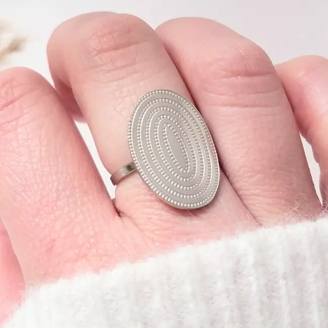 Bague argentée à spirale portée au doigt, bijou moderne pour femme sur main claire