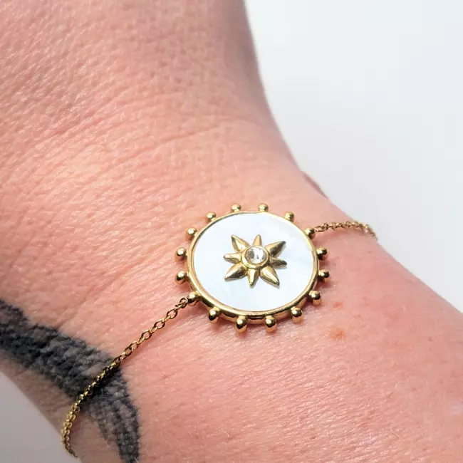 Bracelet solaire nacre porté au poignet avec tatouage visible