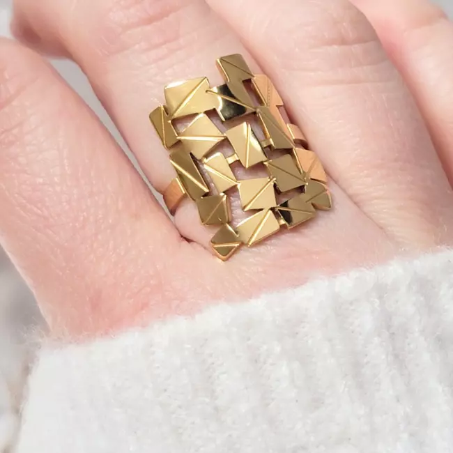 bague moderne dorée portée sur doigt femme pull blanc