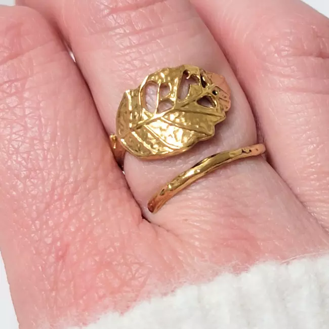 bague feuille dorée portée au doigt sur main féminine