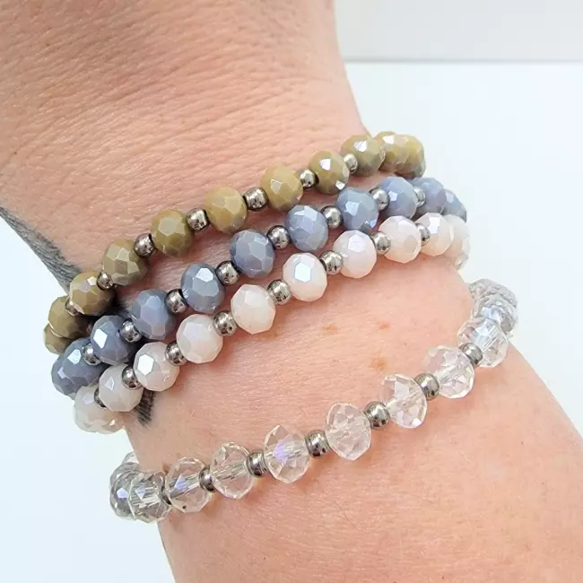 Bracelets empilés en perles facettées marron,bleu, rose et transparente portés ensemble.